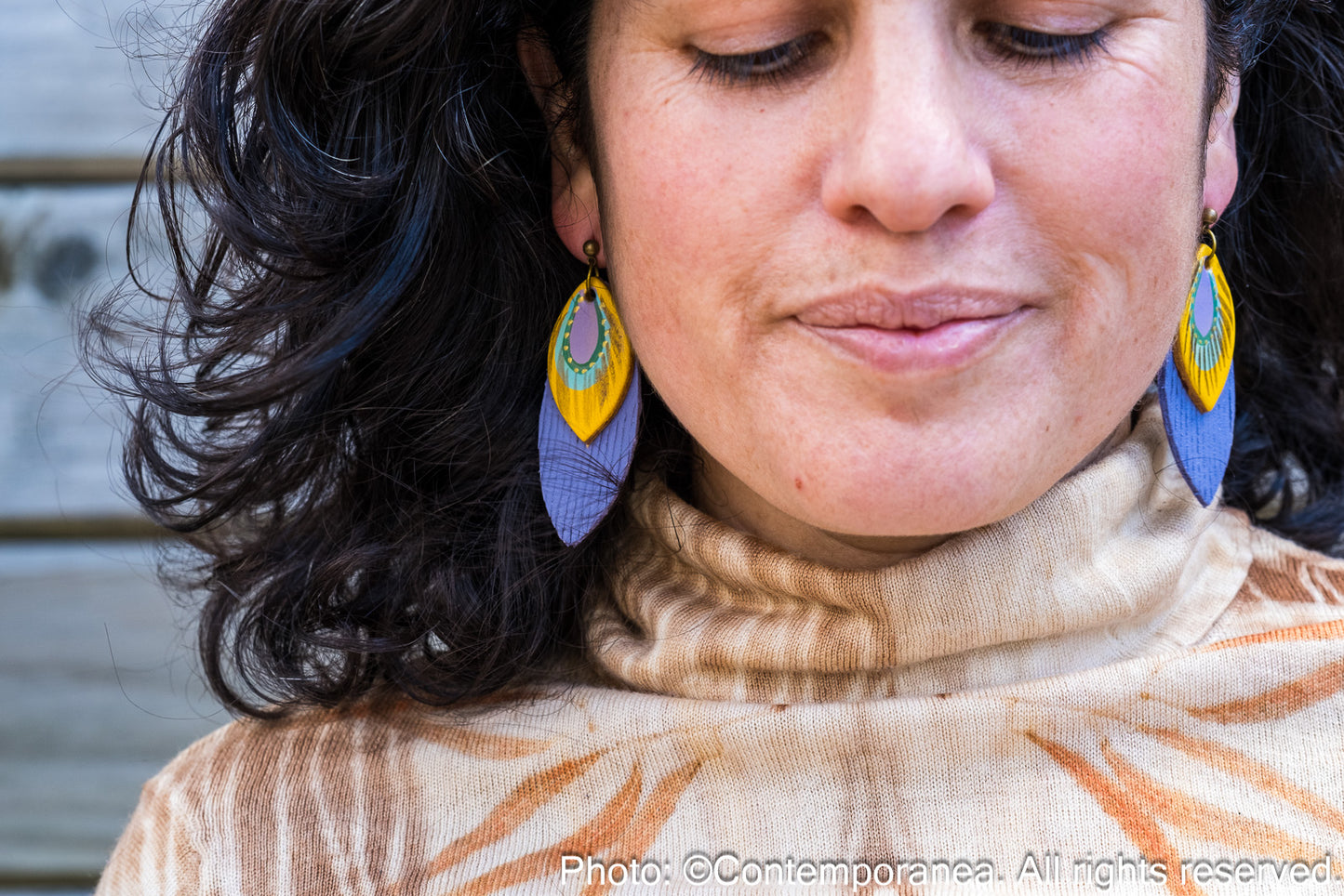 Close-up of a person wearing colorful earrings with a blurred background