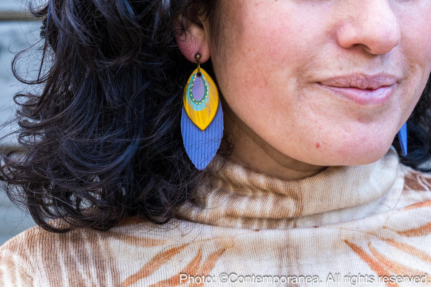 Close-up of a person wearing colorful earrings with a blurred background