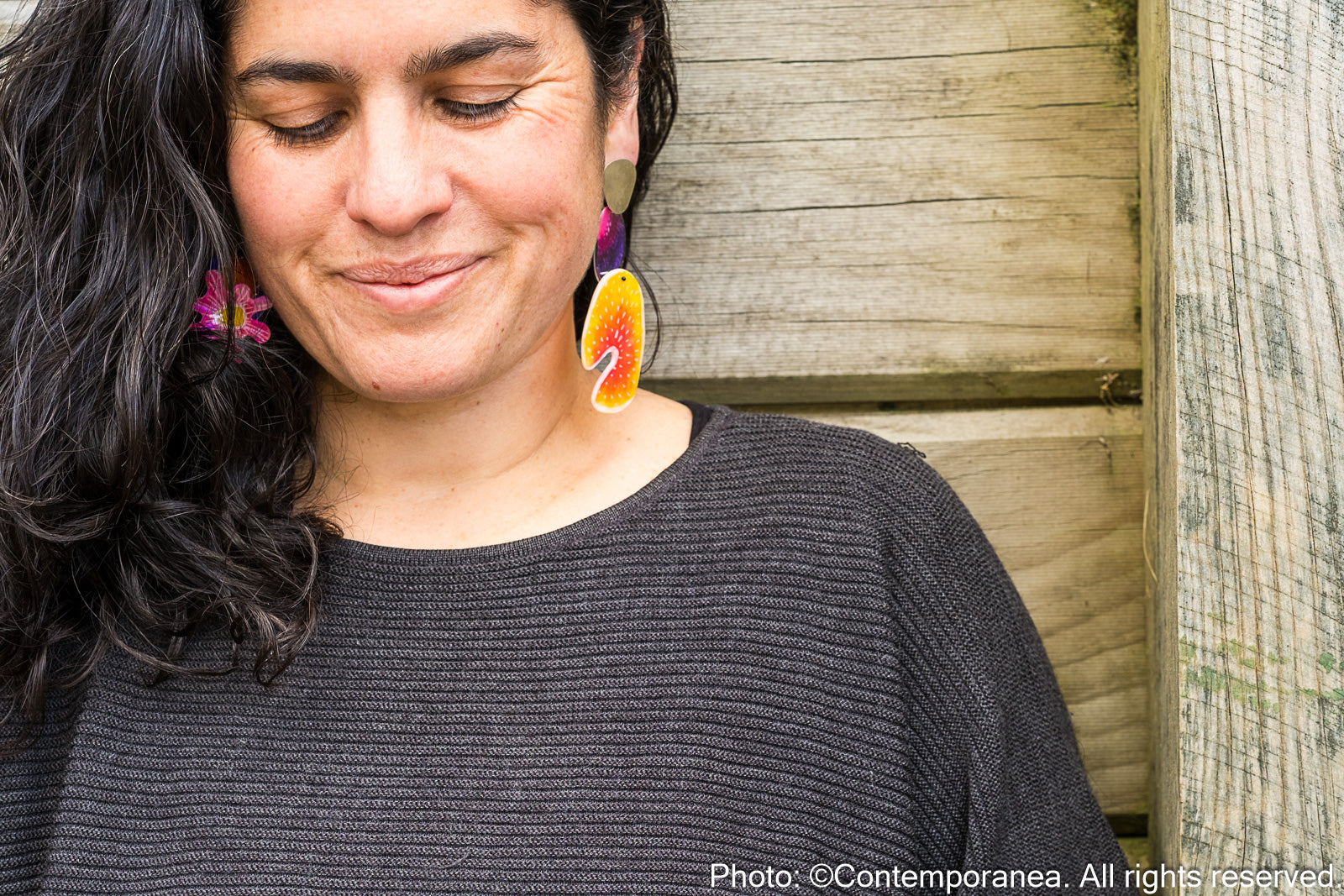 Woman wearing colorful earrings with a wooden background